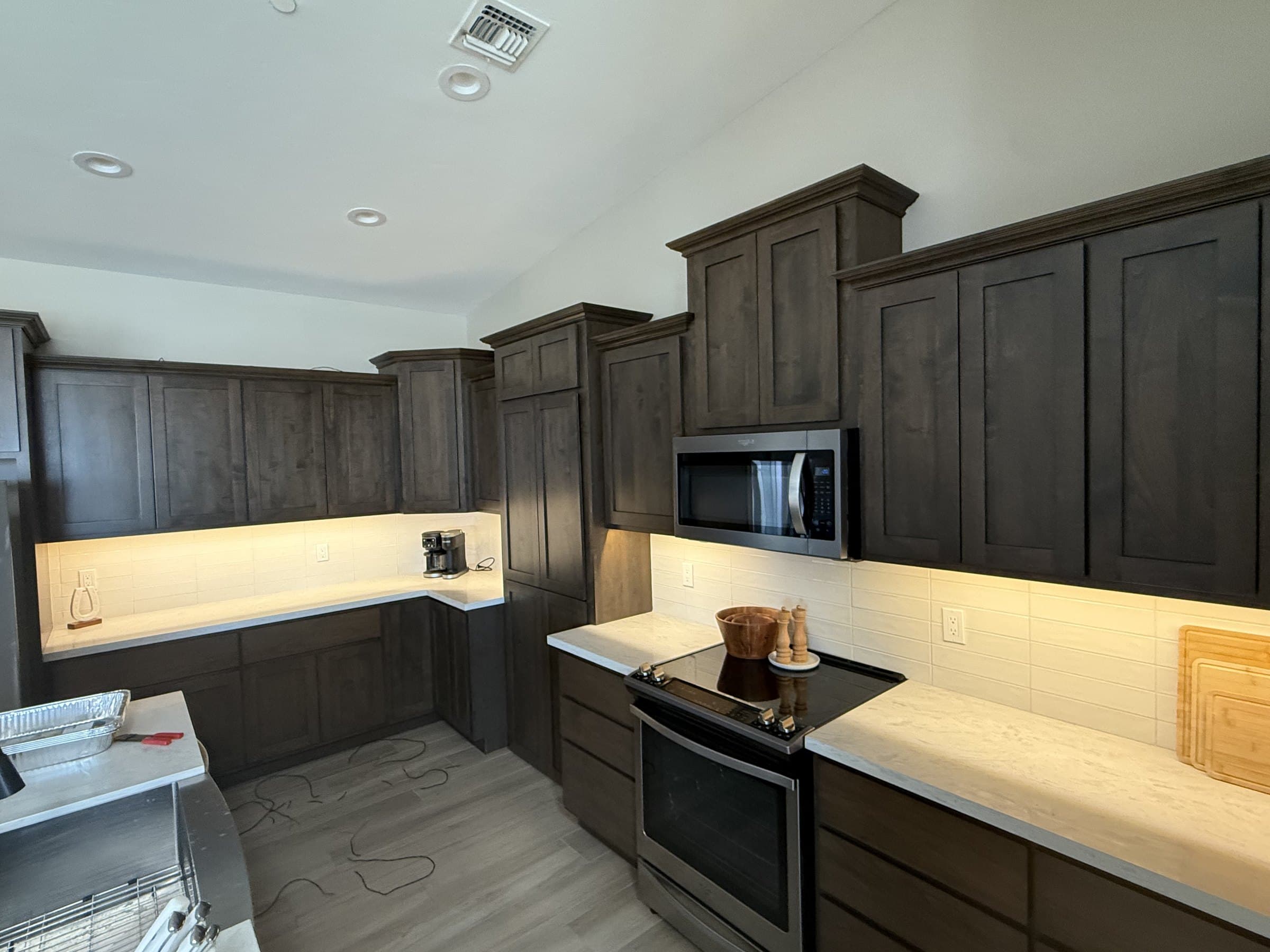 Custom dark-stained kitchen cabinets with warm under-cabinet LED lighting glowing across the countertops