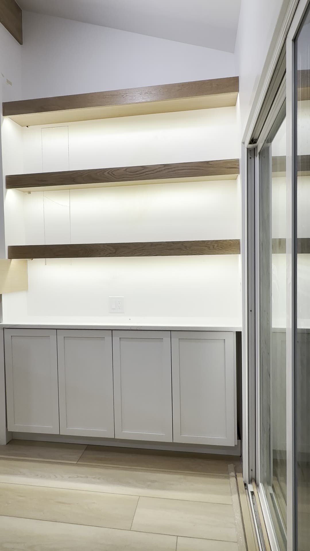 Floating wood shelves with hidden LED reveal lighting glowing warm white from behind