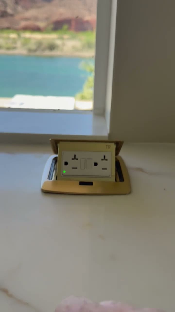Hidden flush-mount GFCI outlet with the cover flipped open, set in a marble countertop overlooking Lake Havasu
